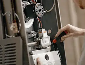Furnace repair technician inspecting internal components and wiring in Miami, FL